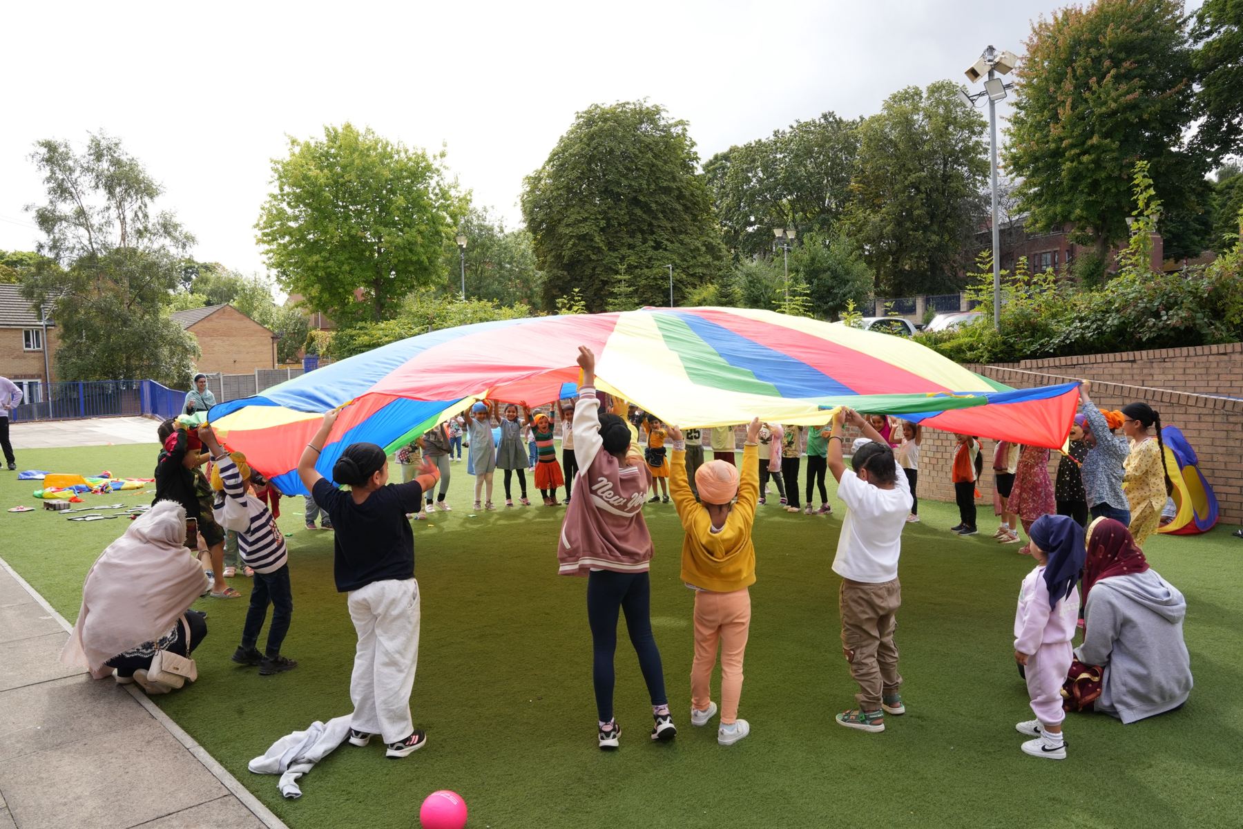 Children holding up a rainbow parachute together at a Sikh Inspiration event