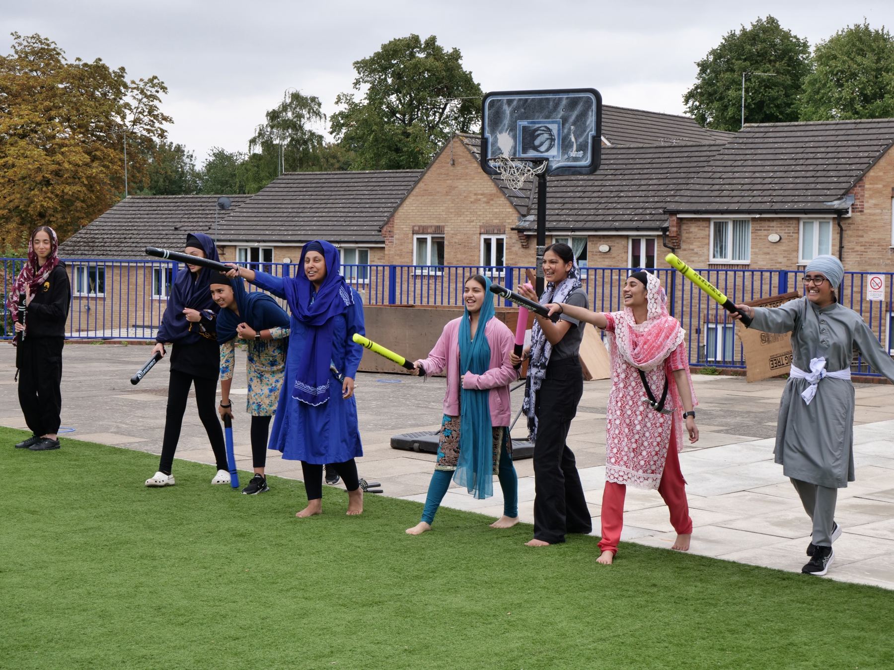 Students practising Gatka moves with foam sticks outdoors