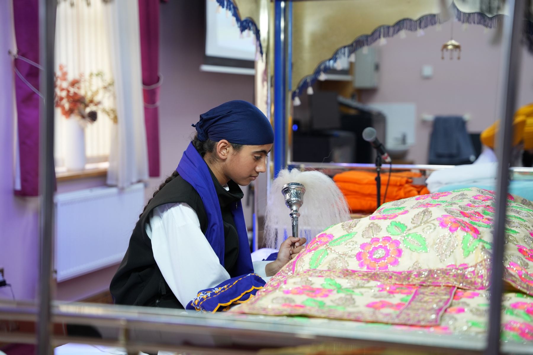 A young Sikh doing seva at the Guru Granth Sahib