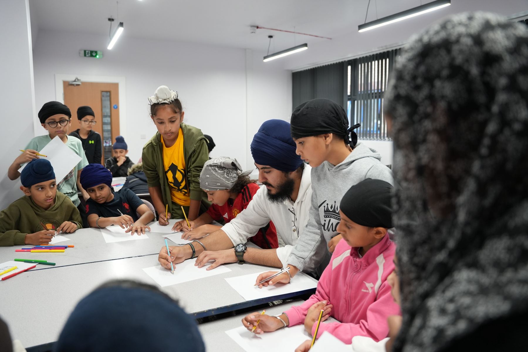 A teacher working with children around a table in Sikhi Classes